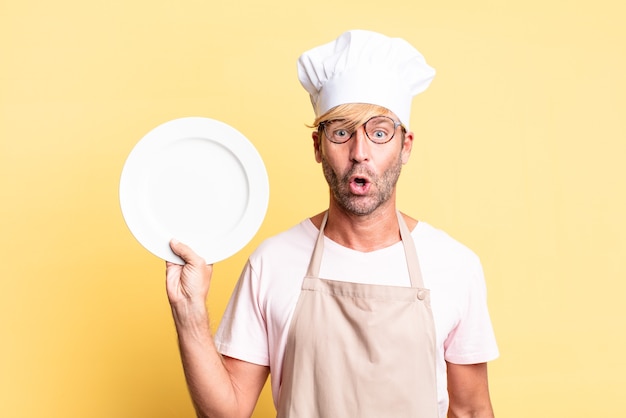 Hombre adulto rubio guapo chef con un plato vacío