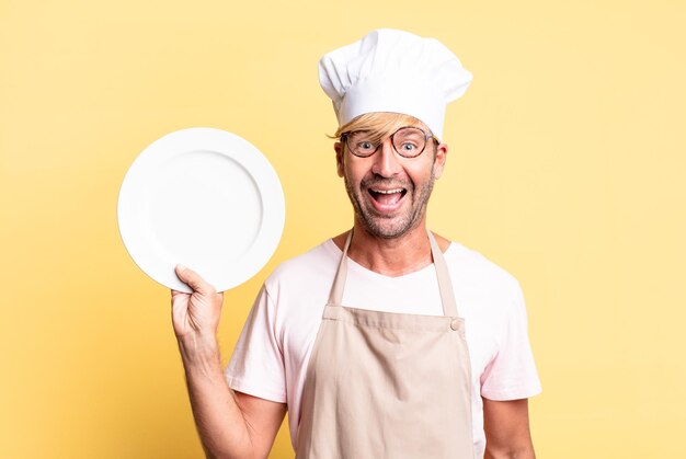 Hombre adulto rubio guapo chef con un plato vacío