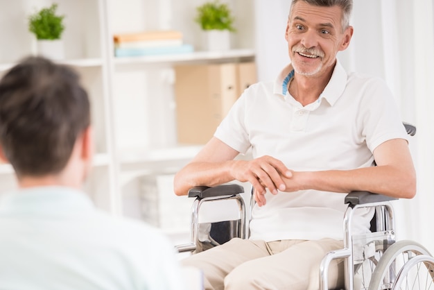 Hombre adulto sentado en casa y hablando con su padre anciano.