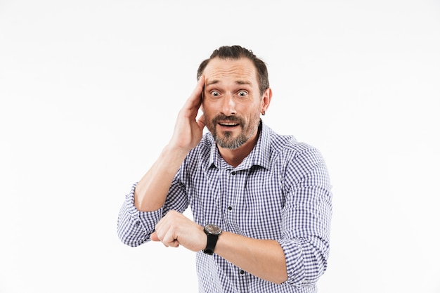 Hombre adulto sorprendido mirando reloj asustado.