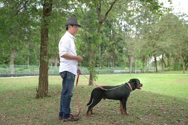 Hombre adulto y su perro mascota en el parque Vista lateral