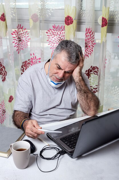 Hombre adulto trabajando en casa con máscara protectora