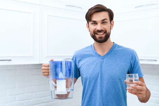 El hombre adulto se vierte agua del filtro de agua en vidrio.