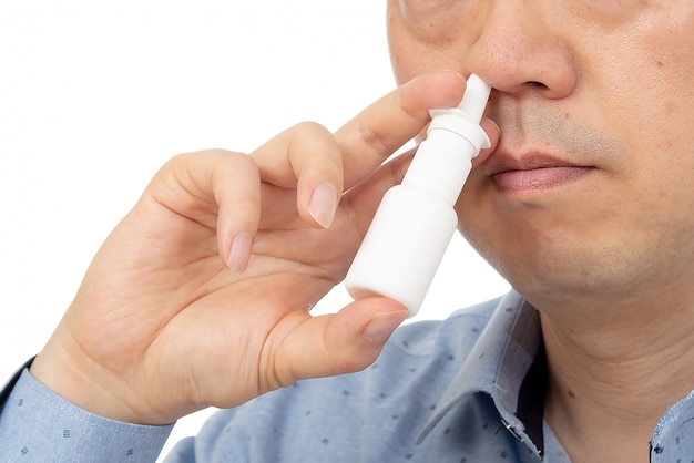 Un hombre con un aerosol nasal en la mano en blanco