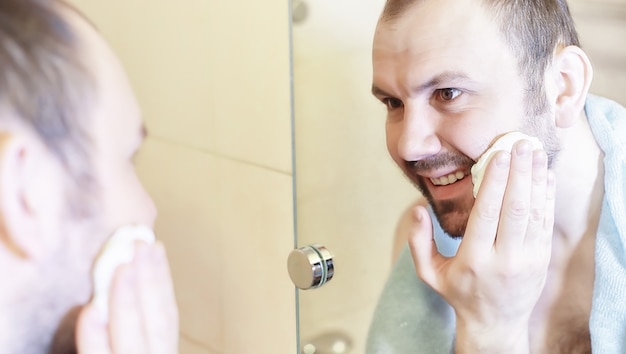 Un hombre se afeita en el baño por la mañana antes del trabajo.