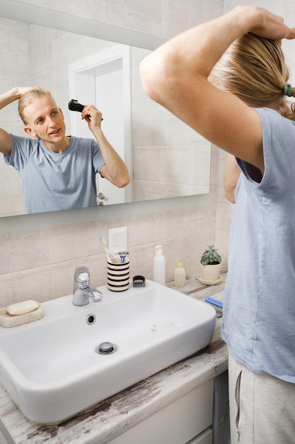 Hombre afeitado bigotes de pelo por maquinilla de afeitar eléctrica por sí mismo en casa