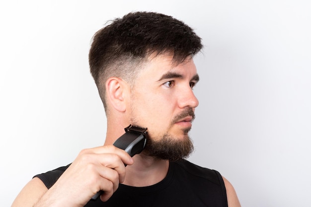 Hombre afeitándose la barba con una recortadora