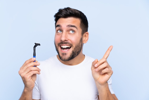 Hombre afeitándose la barba sobre una pared aislada