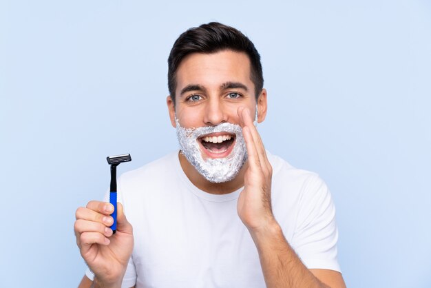 Hombre afeitándose la barba sobre una pared aislada