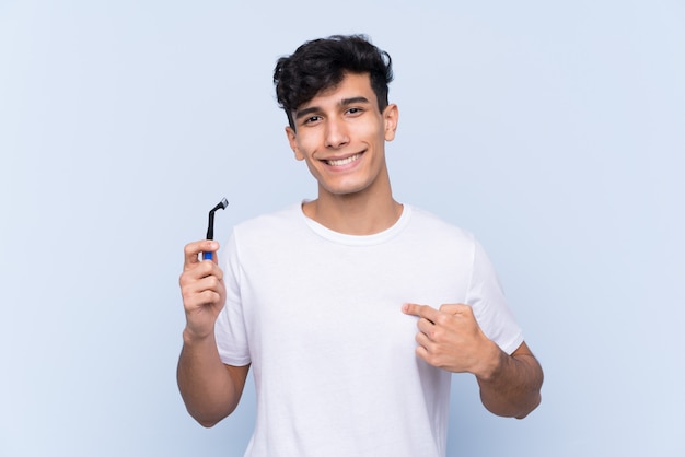 Hombre afeitándose la barba sobre una pared aislada