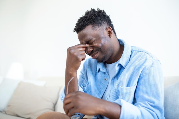 Hombre africano con anteojos se frota los ojos que sufren de ojos cansados concepto de enfermedades oculares