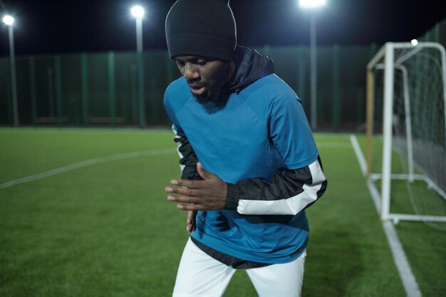 Hombre africano barbudo corriendo por el campo de fútbol