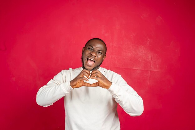 Un hombre africano barbudo sonriente hace un gesto de corazón demuestra un signo de amor expresa buenos sentimientos