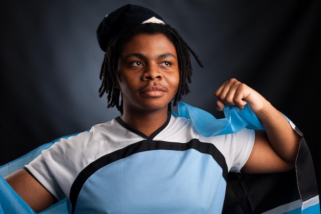 Hombre africano de Botswana con una bandera sonriendo en un estudio fotográfico contra un fondo oscuro