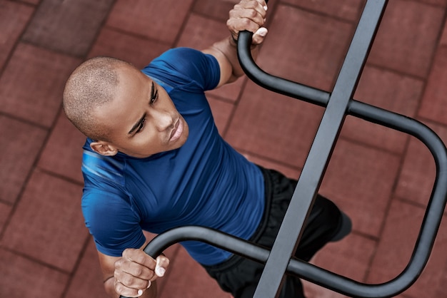 Un hombre africano está tirando hacia arriba en la vista superior de primer plano de gimnasio al aire libre