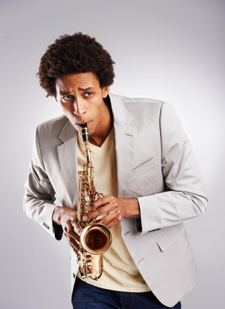 Foto hombre africano feliz y música tocando el saxofón con ropa y ropa casual en el estudio músico confiado de jazz e instrumento con traje de moda para la actuación de la banda sobre fondo blanco