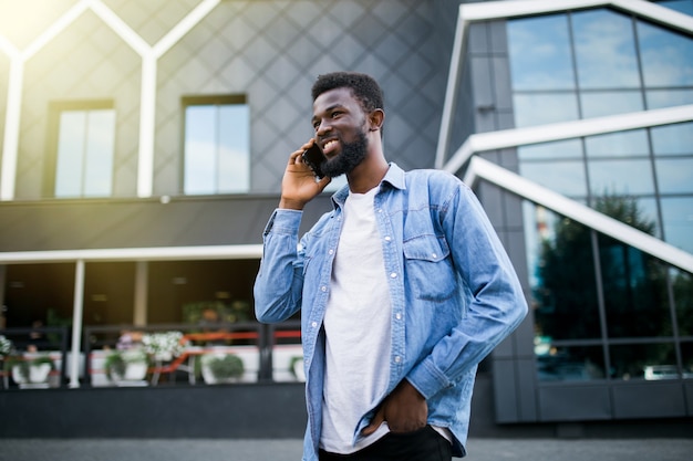 Hombre africano guapo hablando por teléfono en el parque.