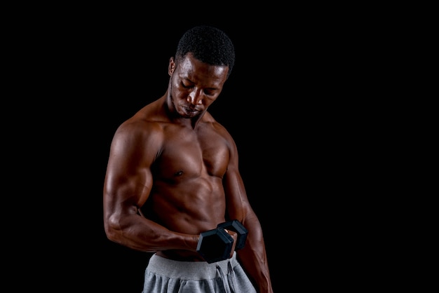 Hombre africano joven sano que ejercita con pesa de gimnasia.