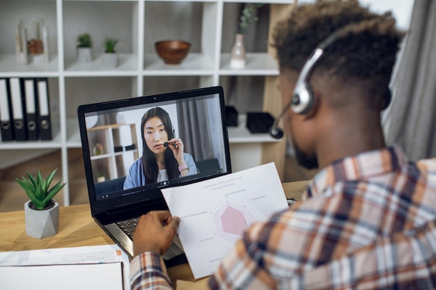 Hombre africano y mujer asiática teniendo videoconferencia