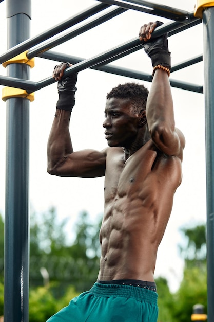 Hombre africano musculoso haciendo flexiones en el parque Fuerte atleta masculino haciendo ejercicio al aire libre