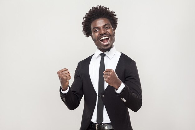 Hombre africano optimista que se regocija por un nuevo contrato. tiro del estudio, fondo gris
