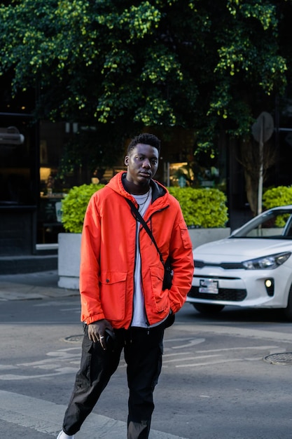 Hombre africano posando en la calle en una ciudad con coche en el fondo.