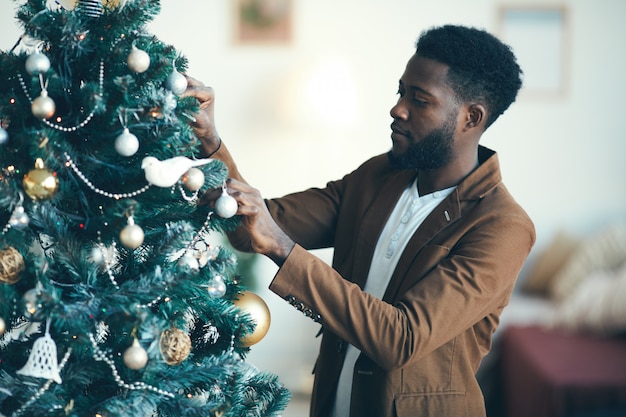 Hombre africano que adorna el árbol de Navidad