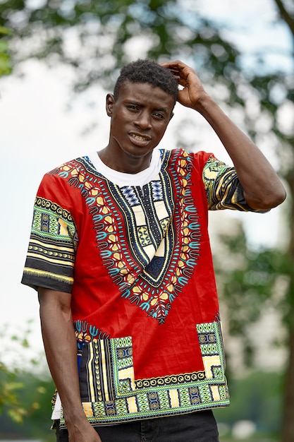 Un hombre africano con ropa nacional sudafricana, un joven negro descansando en un parque con ropa nacional.