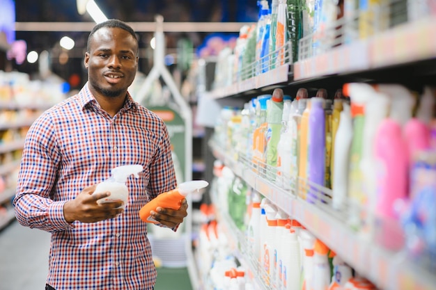 Hombre africano sosteniendo una botella de productos químicos para el hogar en una gran tienda