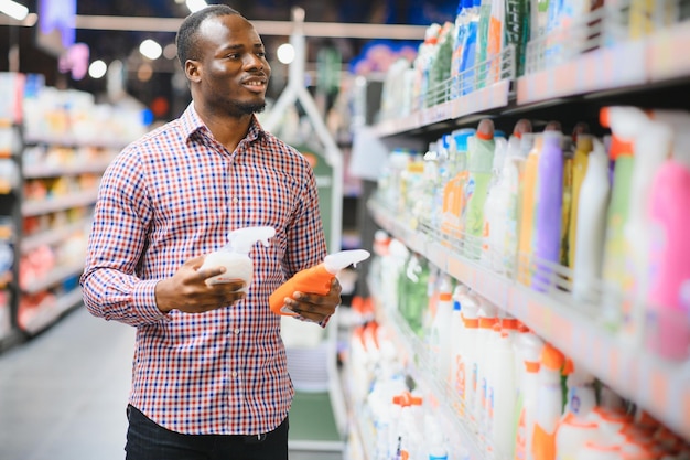Hombre africano sosteniendo una botella de productos químicos para el hogar en una gran tienda