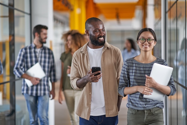 Hombre africano sosteniendo smartphone y hablando con mujer