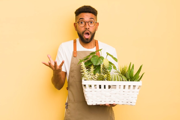 Hombre afro cool asombrado y asombrado con un increíble concepto de planta y jardinero sorpresa