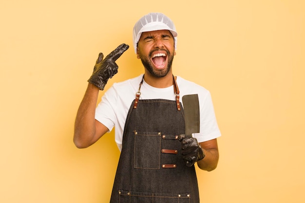 Hombre afro cool que parece infeliz y estresado gesto de suicidio haciendo el concepto de carnicero de armas