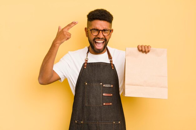 Hombre afro cool que parece infeliz y estresado gesto de suicidio haciendo repartidor de señales de pistola y concepto de comida rápida