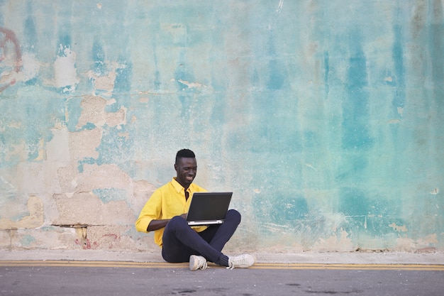 Hombre afro felizmente usando una computadora portátil