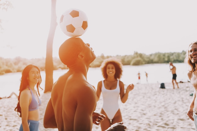 Hombre afro golpea el balón de fútbol con la cabeza en la puesta del sol