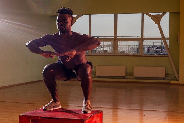 Hombre afro haciendo ejercicio con una caja en forma en un gimnasio