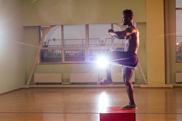 Hombre afro haciendo ejercicio con una caja en forma en un gimnasio