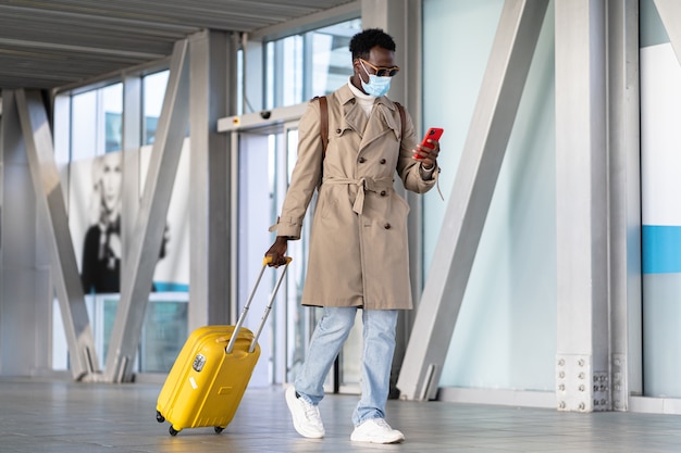 Hombre afro milenario caminando con maleta en el aeropuerto