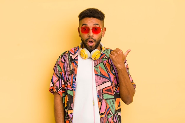 Hombre afro negro mirando asombrado por el concepto de gafas de sol y auriculares de incredulidad