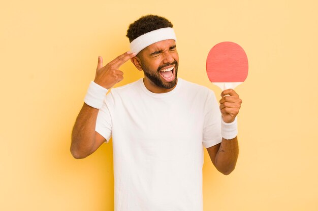 Hombre afro negro que parece infeliz y estresado gesto de suicidio haciendo concepto de ping pong de signo de pistola