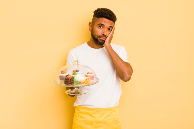 Hombre afro negro que se siente aburrido, frustrado y con sueño después de un tedioso concepto de pasteles caseros