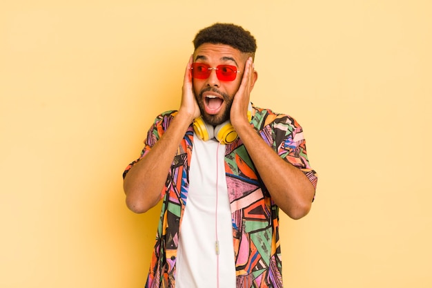 Hombre afro negro que se siente feliz emocionado y sorprendido concepto de gafas de sol y auriculares