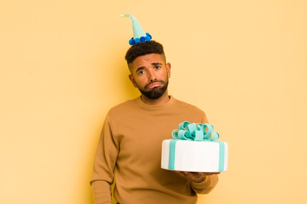 Hombre afro negro que se siente triste y quejumbroso con una mirada infeliz y un concepto de cumpleaños llorando