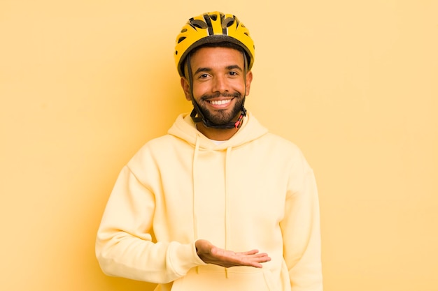 Hombre afro negro sonriendo alegremente sintiéndose feliz y mostrando un concepto de bicicleta conceptual