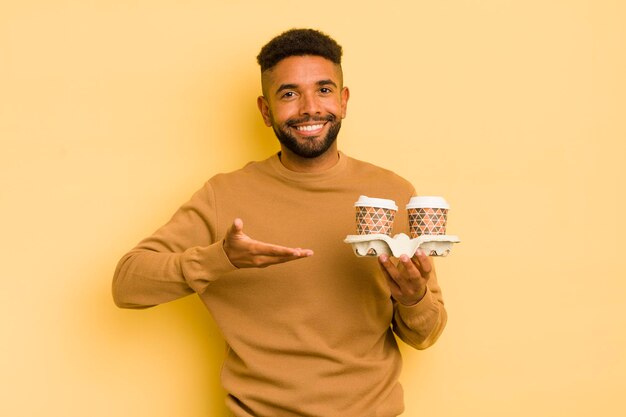 Hombre afro negro sonriendo alegremente sintiéndose feliz y mostrando un concepto de café para llevar