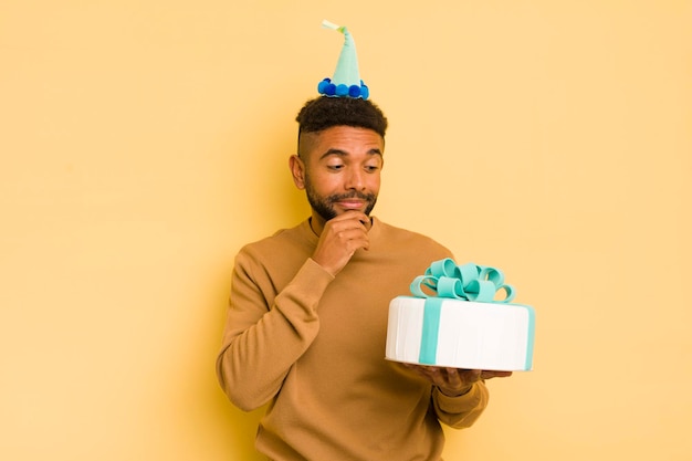 Hombre afro negro sonriendo con una expresión de confianza feliz con la mano en el mentón concepto de cumpleaños