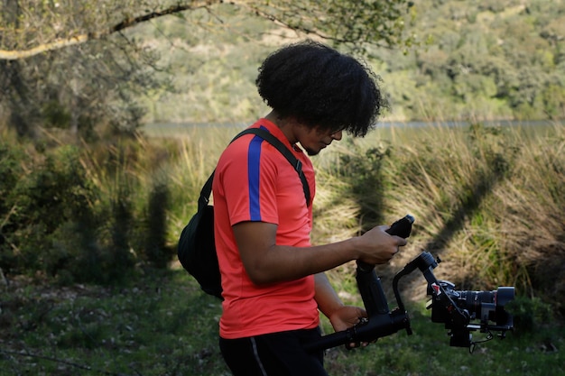 Hombre con afro sosteniendo un cardán con cámara en el campo