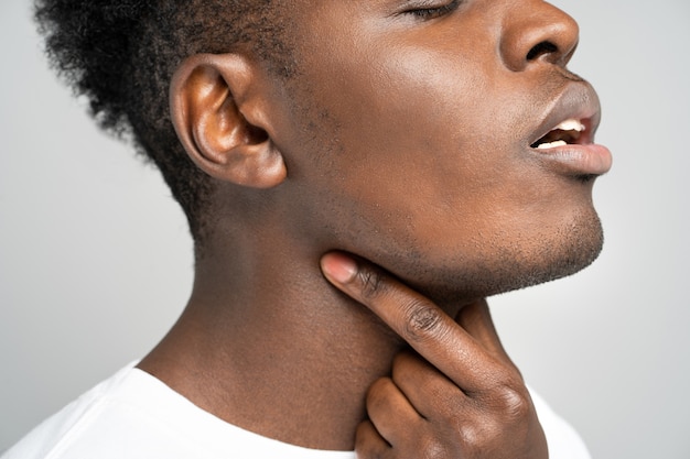 Hombre afro toca los dedos del dolor de garganta