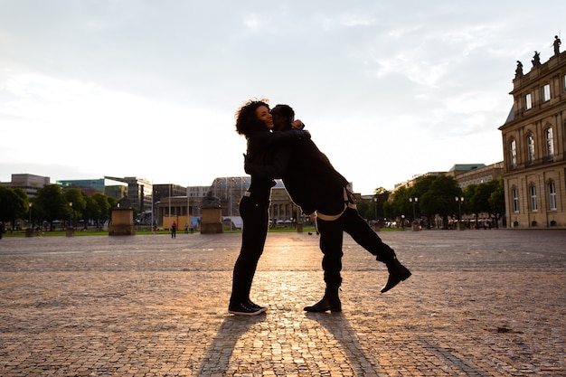 Hombre afroamericano abrazando a la novia en la ciudad